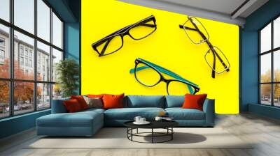 Set of glasses with transparent lenses on yellow background top view Wall mural