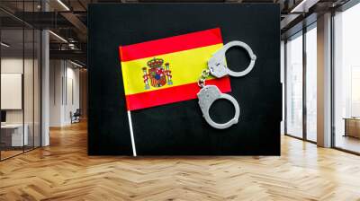 Violation of law, law-breaking concept. Metal handcuffs on Spanish flag on black background top view Wall mural