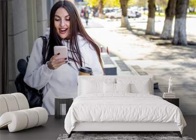 Young woman with smart phone and coffee outdoor Wall mural