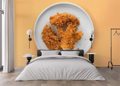 Flat lay or top down view cooked fried crispy fried chicken on a white round ceramic plate with plain pale orange isolated color as background Wall mural