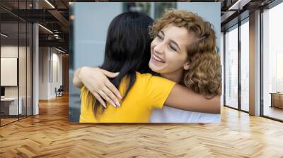 african black woman hugging caucasian white woman friend; concept of skin color tolerance, world peace, ethnicity understanding, international women friends of different skin color and ethnicity Wall mural