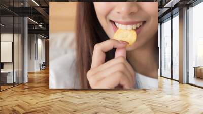 happy, smiling woman eating potato chips or crispy fried potato; unhealthy food or fried food concept; young adult asian persian woman or asian middle east model Wall mural