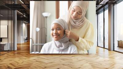 Happy smiling muslim woman help dressing up her friend, concept of islamic sisterhood, friendship among muslim people Wall mural