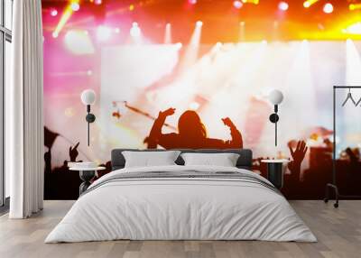 The crowd with their hands up enjoys music concert. Fan silhouette on stage background. Wall mural