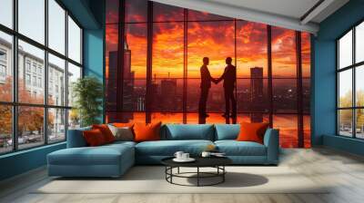 two business people shaking hands in front of a window with skyscrapers in the background at sunset or dawn Wall mural