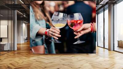 Two women holding a gin and tonic and toasting during a music festival Wall mural