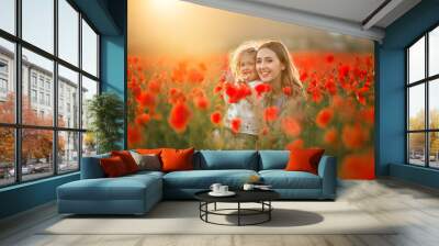 Beautiful smiling child girl with young mother are having fun in field of poppy flowers over sunset lights Wall mural