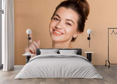 Happy smiling girl with perfect skin with moisturizing face cream on a cheek. Skin care and health concept. Wall mural