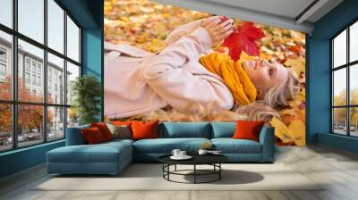 Portrait of pretty blonde teen girl lying on the carpet of yellow leaves Wall mural