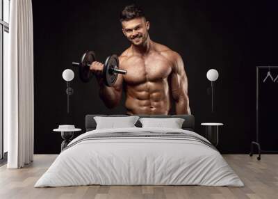 Muscular bodybuilder guy doing exercises with dumbbells Wall mural