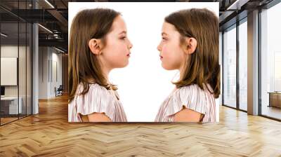 Identical twin girls are looking at each other and smiling. Wall mural