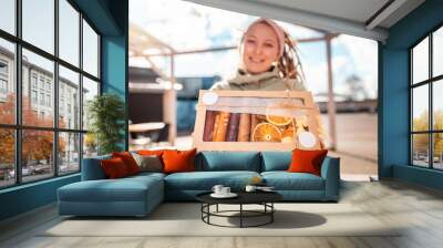 Defocused portrait of a young smiling woman with dreadlocks holding a craft box of dried fruits and pastille. Concept of natural sugar free sweets Wall mural