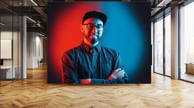 Neon lights. Portrait of a man in a shirt, glasses and cap, with a beard, posing with his arms crossed. Red and blue circle in black background Wall mural