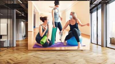 New normal. A group of young women in protective masks communicate in a yoga studio. The concept of a sporty lifestyle and protection against coronavirus Wall mural