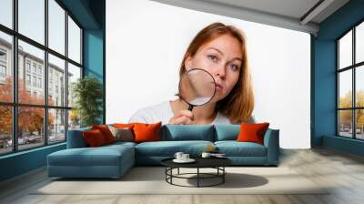 Portrait of a young woman holding a magnifying glass to her face. White background. The concept of search, research and business Wall mural