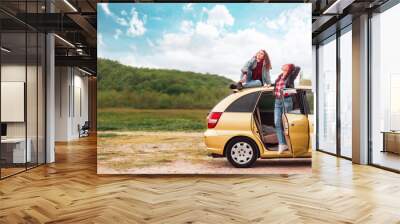 Travel banner. Caucasian mother and her teen daughter dreamy posing by a yellow car. The concept of freedom and travel on a car Wall mural