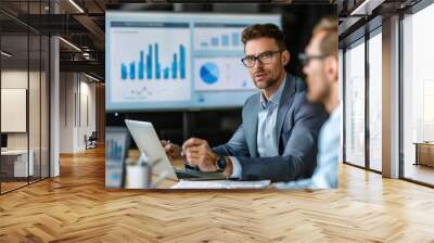 Two professionals discuss insights from data charts while collaborating in a contemporary office environment Wall mural