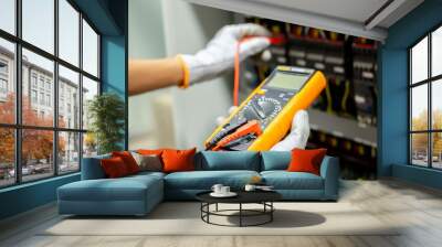 Electrician engineer uses a multimeter to test the electrical installation and power line current in an electrical system control cabinet. Wall mural