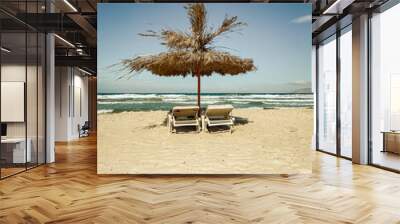 Straw parasol and two lounge chairs on a beach in retro look. Wall mural