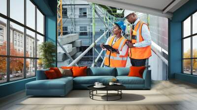 Building a city their community deserves. a young man and woman using a digital tablet while working at a construction site. Wall mural