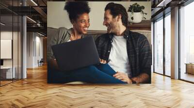 Laptop, entertainment and interracial with a couple streaming a movie using an online subscription service to relax. Computer, watching or internet with a man and woman bonding together over a film Wall mural