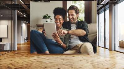 There are so many apps to choose from. a happy young couple using a digital tablet together while relaxing on a couch at home. Wall mural