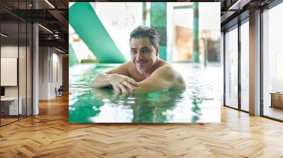 Smiling man relaxing in indoor swimming pool. Concepts of spa, wellness, vacation. Wall mural