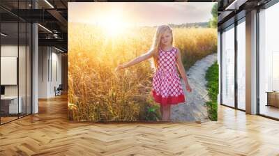 Little girl on a wheat field in the sunset. Wall mural