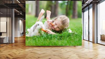 Little girl playing with white rabbit outdoor Wall mural