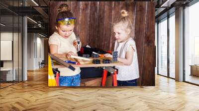 Two little girls making very interesting creations with tools and wood at home Wall mural