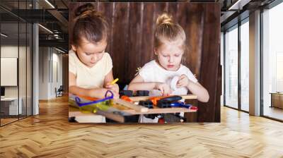 Two little girls making very interesting creations with tools and wood at home Wall mural