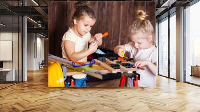 Two little girls making very interesting creations with tools and wood at home Wall mural