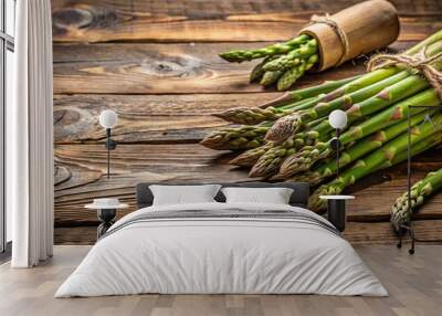 A rustic wooden table with a collection of fresh asparagus, with more asparagus nearby Wall mural