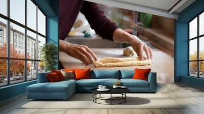 female hands roll and shape dough to bake an easter braid Wall mural