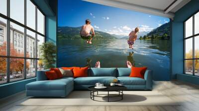 girl and boy jumping in lake water at summer holiday Wall mural