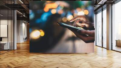 Businesswoman with smartphone using application for calling taxi online walking on city street night, female hands with internet connection texting friend via mobile phone on background bokeh light Wall mural