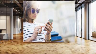 Hipster texting message on smartphone or technology, mockup of blank screen. Girl using cellphone on building castle background close. Tourist female hands holding gadget on blurred summer backdrop Wall mural