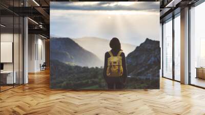 Hipster young girl with bright backpack enjoying sunset on peak of foggy mountain. Tourist traveler on background valley landscape view mockup. Hiker looking sunlight flare in trip in northern spain Wall mural