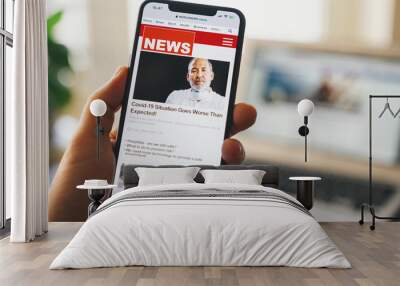 Close up of businessman reading news or articles in a mobile phone screen app. Hand holding smart device. Mockup website. Newspaper and portal on internet. Displayed news are not reality related. Wall mural