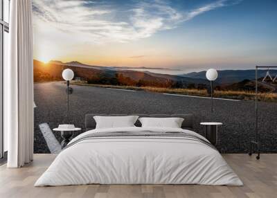 Empty long mountain road to the horizon on a sunny summer day at bright sunset Wall mural