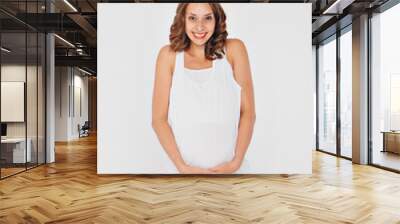 pregnant woman in sportswear on white background. The girl holds her stomach with her mouth wide open and a smile on her face Wall mural