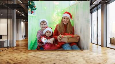 Smiling funny three children in Santa red hat holding Christmas gift in hand. New year concept. Wall mural