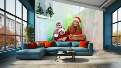 Smiling funny three children in Santa red hat holding Christmas gift in hand. New year concept. Wall mural