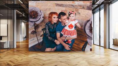 the child in the arms of his mother and father. A woman, man with a child in her arms next to a large flower Wall mural