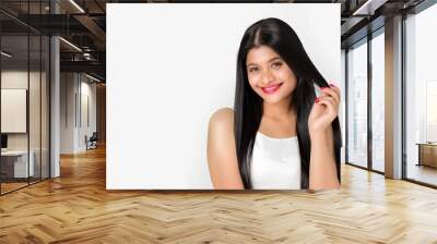 A woman with long black hair touches her shiny smooth straight hair on a white background haircare theme Wall mural