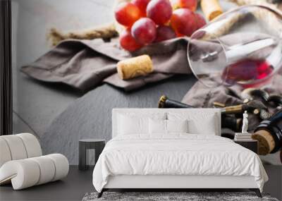 Bottle, corkscrew, glass of red wine, grapes on a table Wall mural