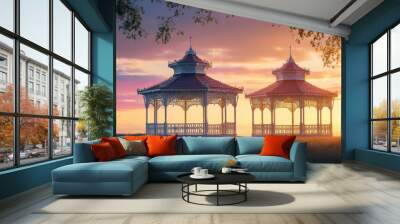 Two ornate gazebos at sunset, surrounded by nature, creating a serene atmosphere. Wall mural