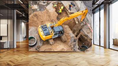 Excavator at a construction site while digging trenches for calcining sewer and drainpipes with a raised bucket, top aerial view. Wall mural