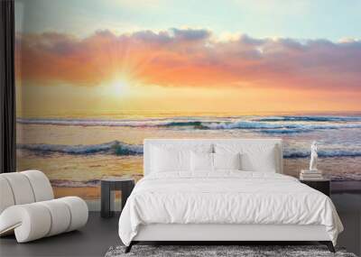 Ocean wave on the beach at sunset time, sun rays. Wall mural