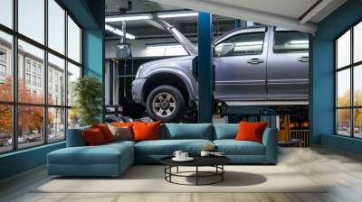 Pickup truck lifted into the air using a mechanical bridge jack in a service garage for car repair and maintenance at night time Wall mural